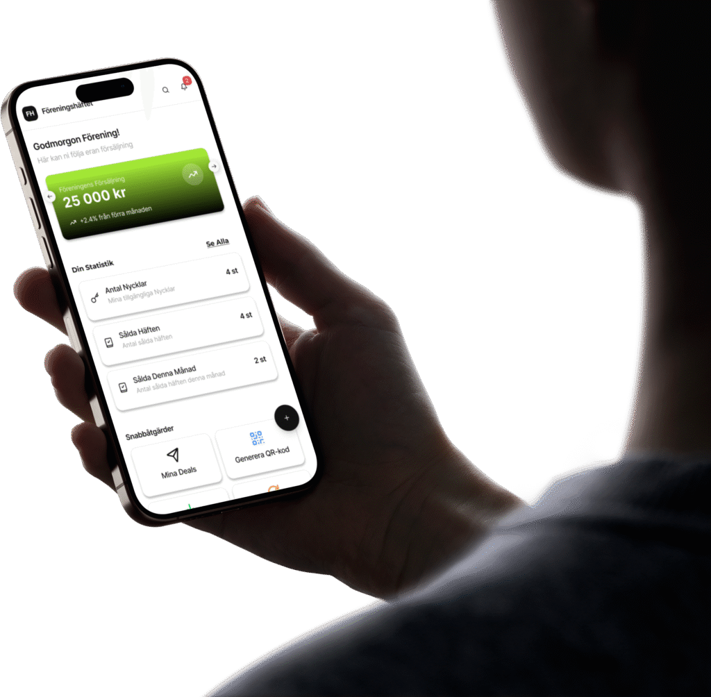 Användare som håller i mobilen och visar Föreningshäftets startsida med statistik och försäljningsöversikt.