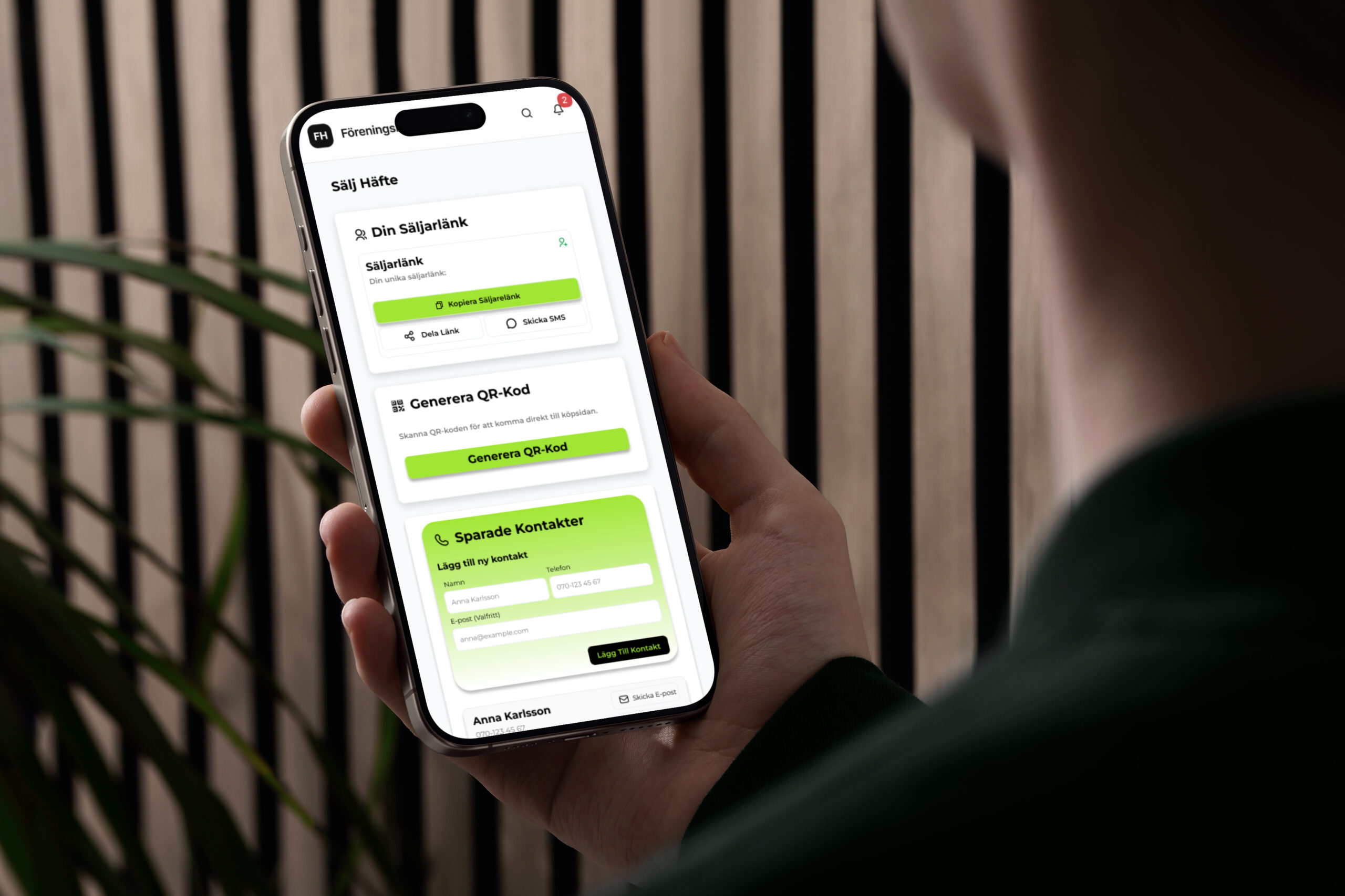 Person håller en mobil där Föreningshäftets säljsida visas, med länkdelning, QR-kod och sparade kontakter.