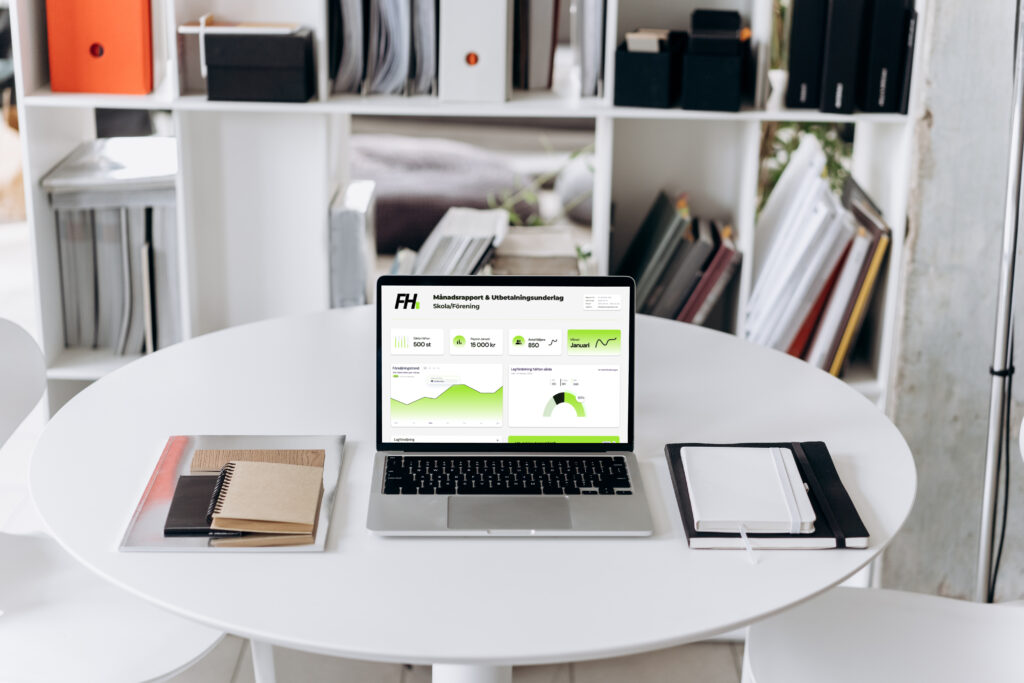 Laptop med Föreningshäftets rapport- och statistikvy öppnad på ett bord i en arbetsmiljö.