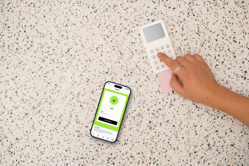 Hand som använder en betalterminal bredvid en iPhone som visar Föreningshäftets aktiveringssida för en deal.